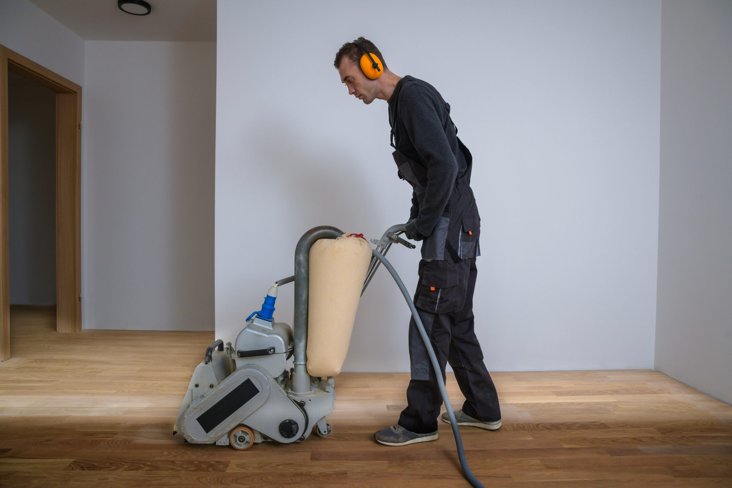 Grief Over Scratches in Egham – technician using a dust-free belt sander on a European oak engineered plank floor to remove scratches before refinishing.