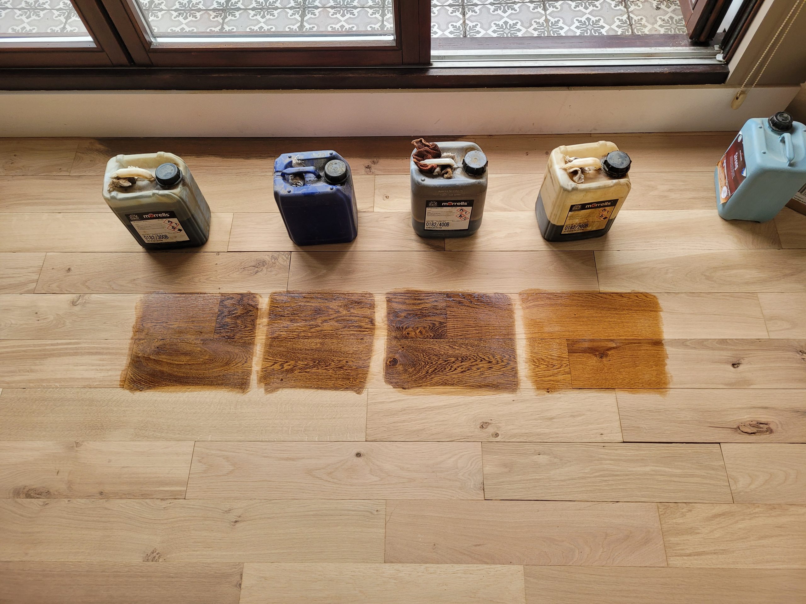 Grief Over Scratches in Egham – stain test swatches on a European oak engineered plank floor to colour-match and disguise surface scratches before finishing.