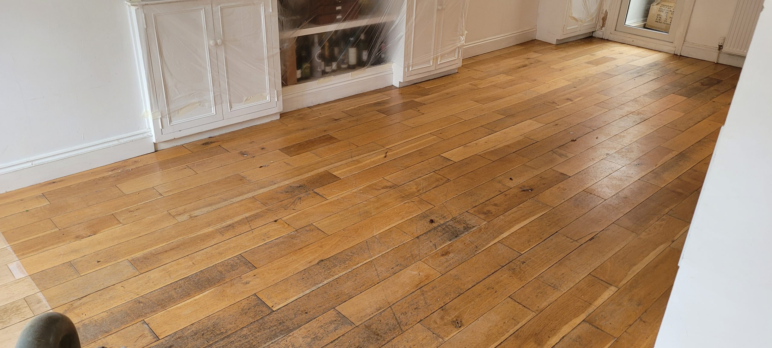Grief Over Scratches in Egham – European oak engineered strip floor before sanding, with surface scuffs, dull patches and traffic staining.