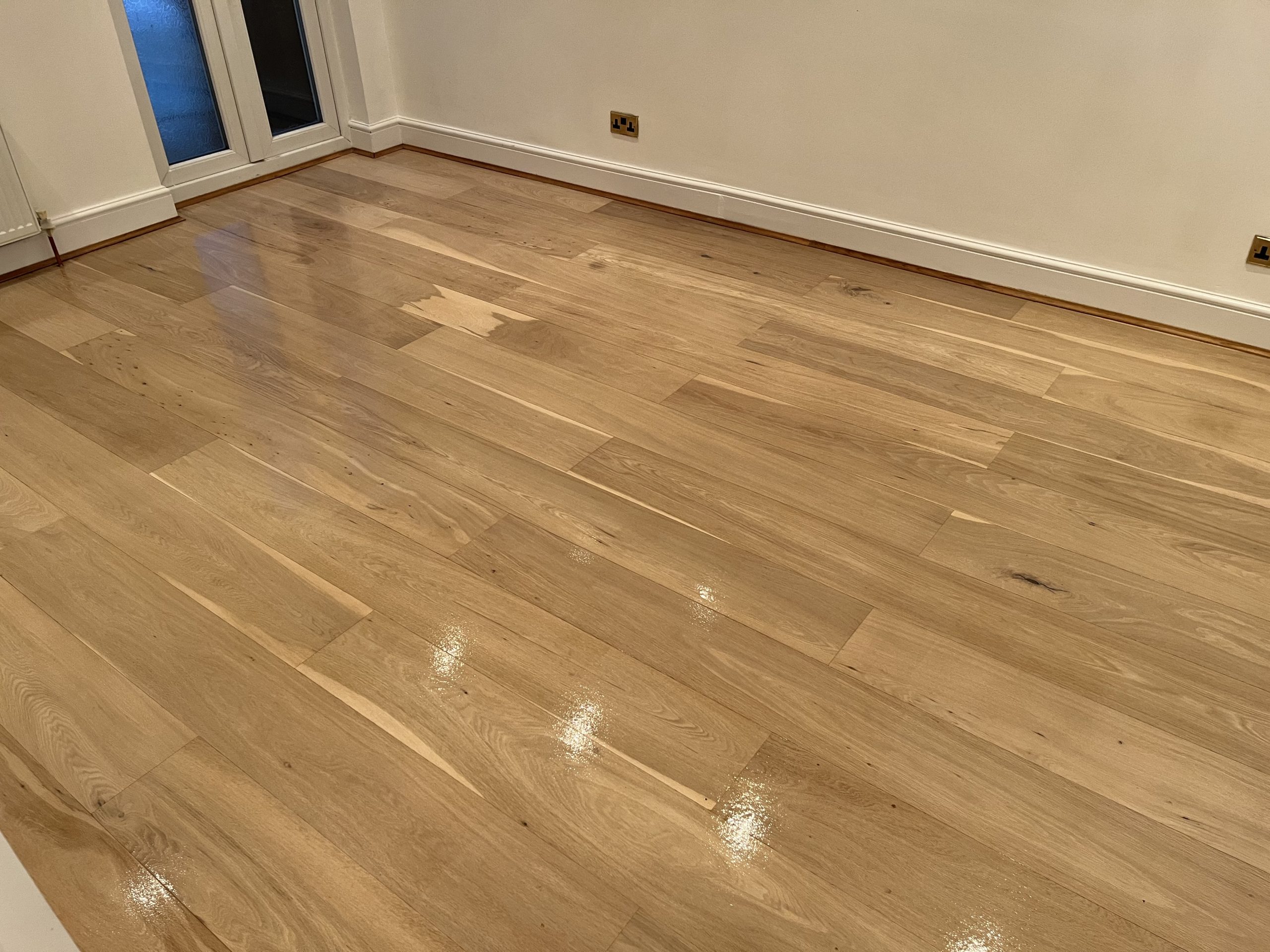 Grief Over Scratches in Egham – oak plank hardwood floor restored with a fresh gloss finish after sanding and sealing, scratches blended and sheen even.