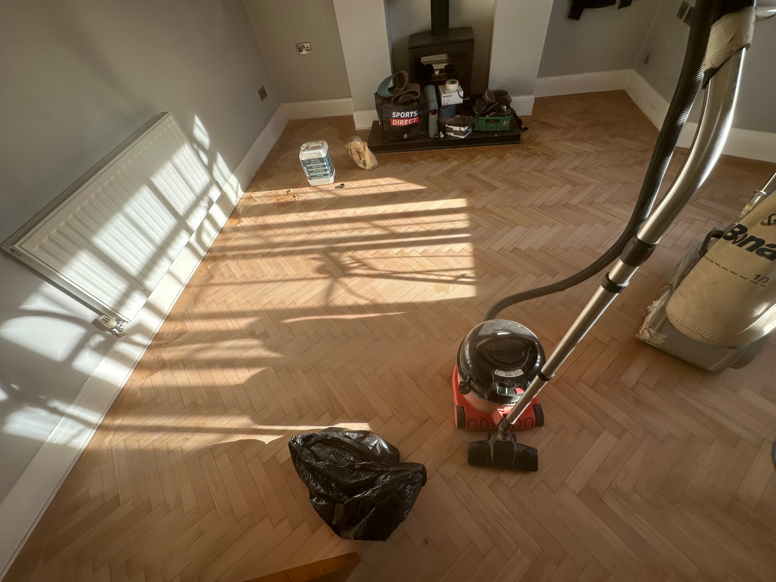 Parquet Floor Sanding in Egham on a light oak herringbone parquet floor, freshly sanded and being vacuumed clean before sealing.