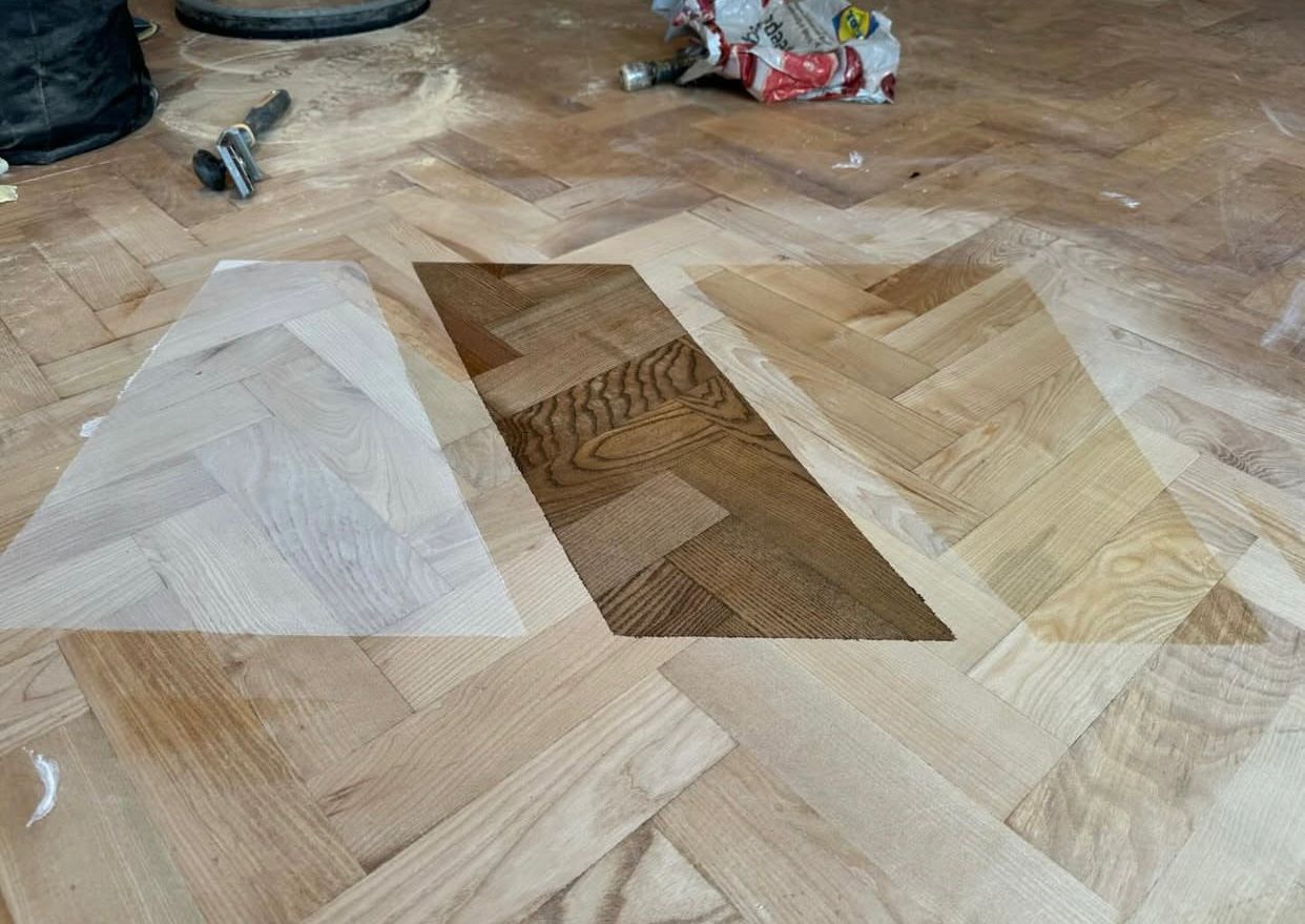Parquet Floor Sanding in Egham showing different stain colour samples tested on a freshly sanded oak herringbone parquet floor.