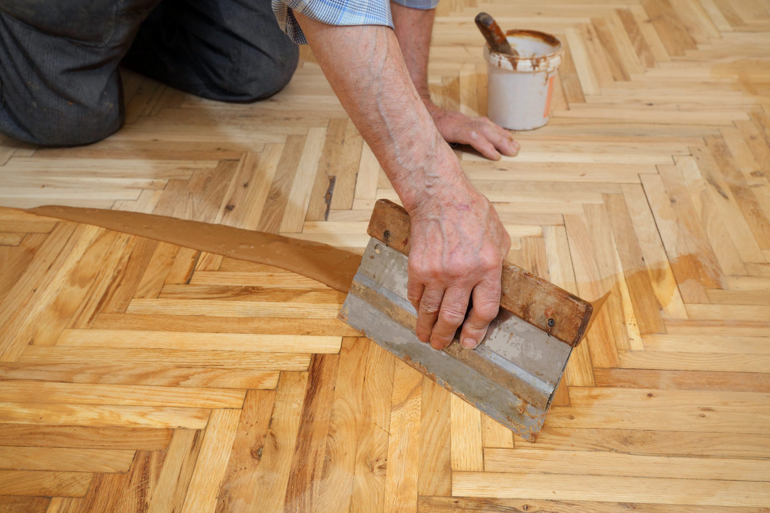 Parquet Floor Sanding in Egham with gap filling on a light oak herringbone parquet floor using a trowel before sealing.