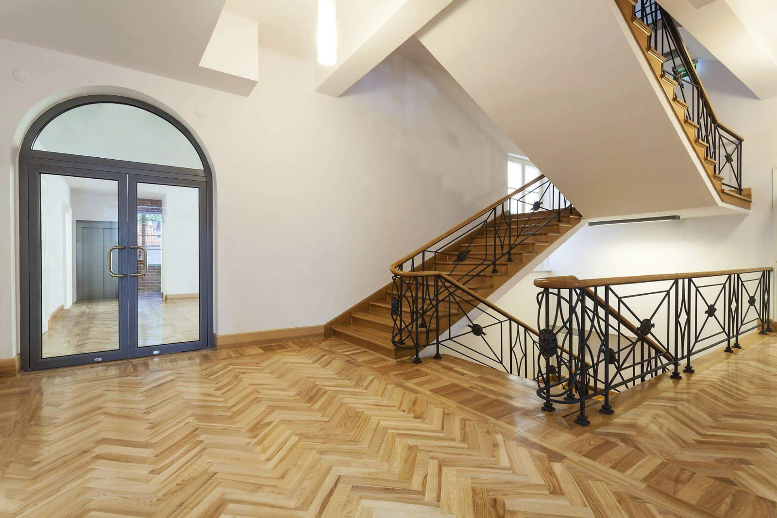 Parquet Floor Sanding in Egham showcasing a beautifully restored light oak herringbone parquet floor in a bright entrance hall and staircase.