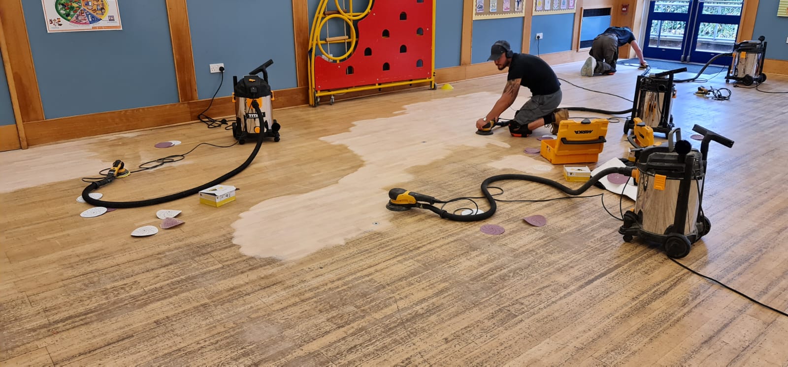 Commercial Floor Sanding in Egham on a maple hardwood school hall floor, with technicians using dust-free sanding machines to restore the worn surface.
