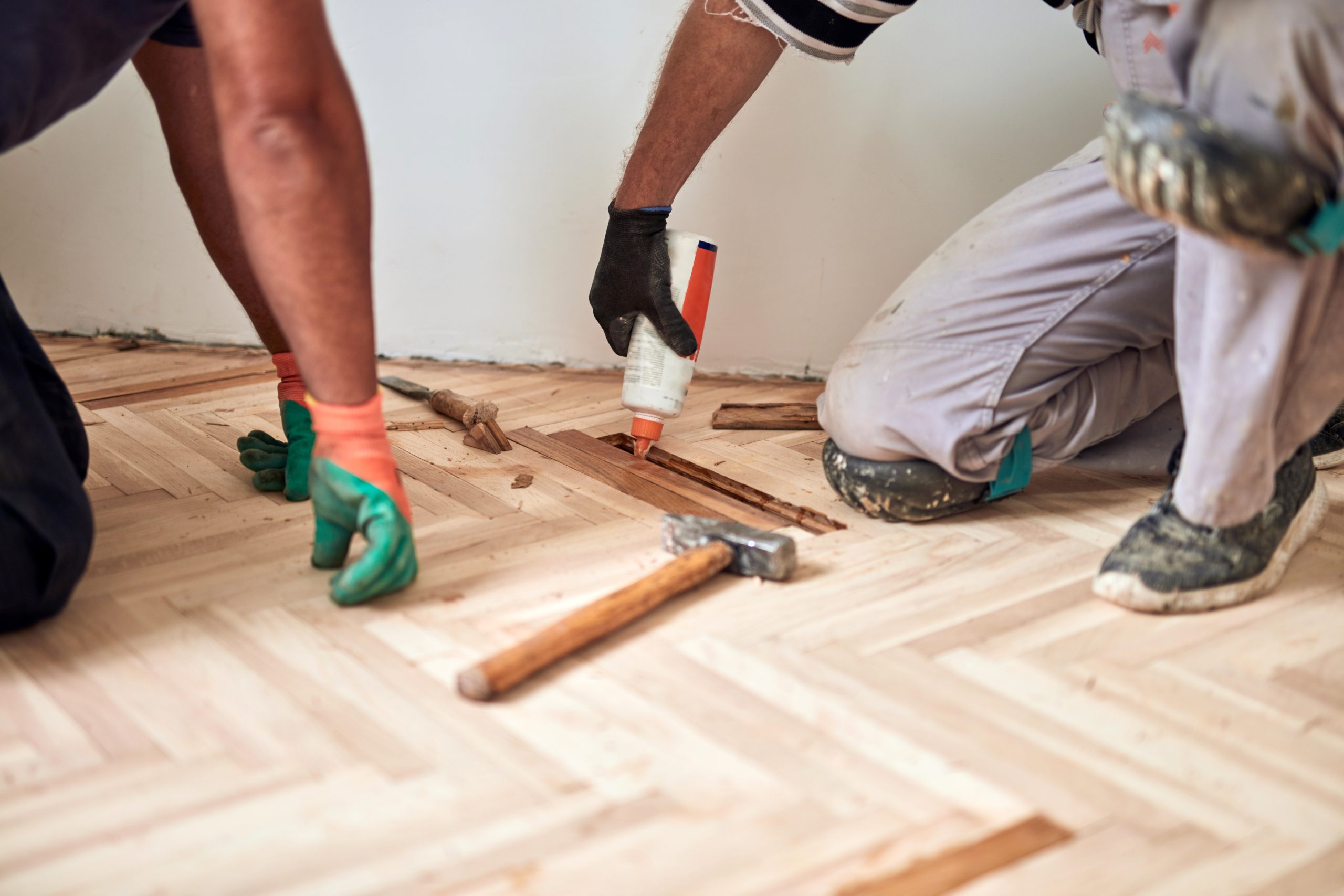 Commercial Floor Sanding in Egham with technicians repairing an oak herringbone parquet wood floor before sanding and refinishing.
