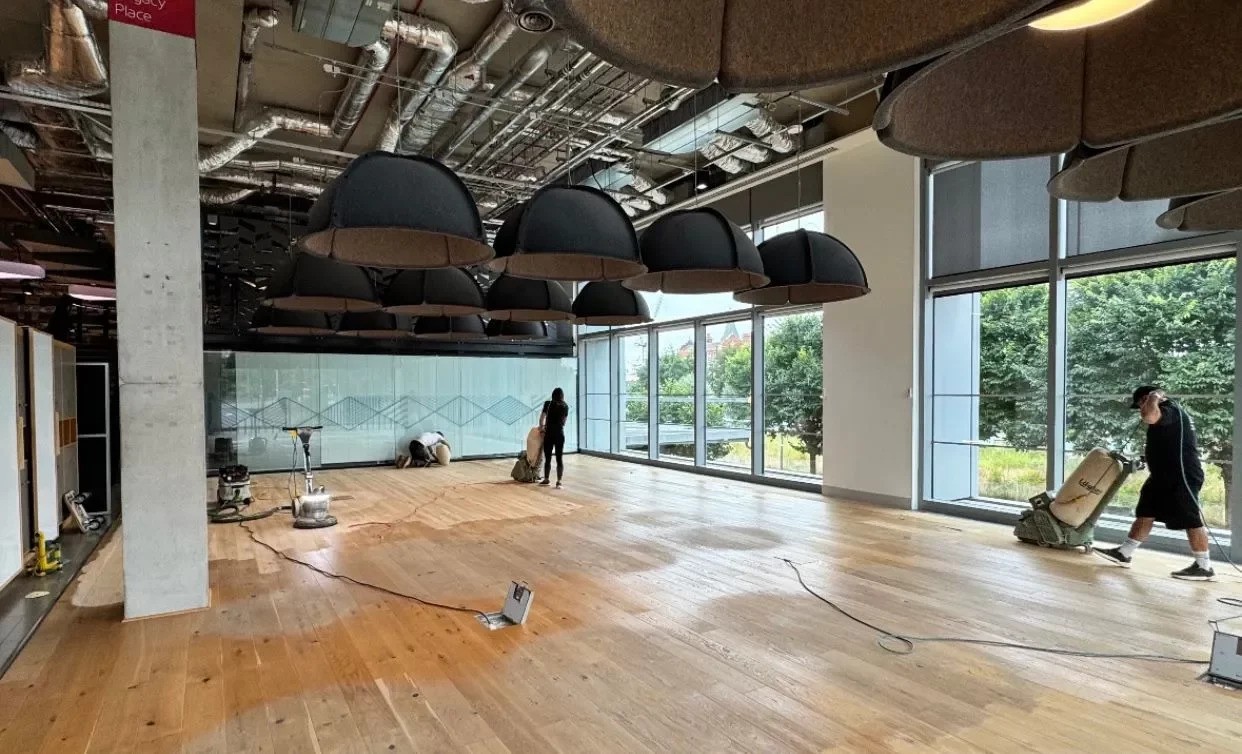 Commercial Floor Sanding in Egham on an oak plank hardwood office floor, with technicians sanding the large open-plan workspace.
